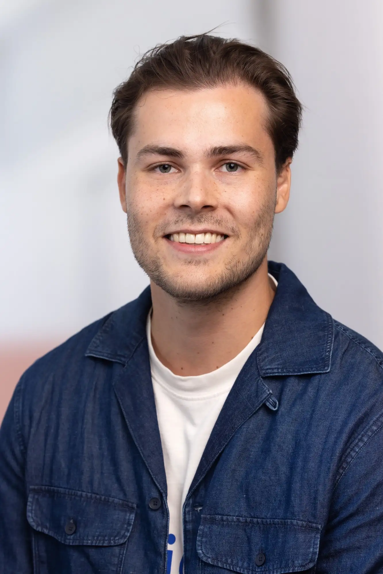 Portretfoto van Luca Giannotta, lachend, in een blauw denim overhemd met een wit T-shirt.
